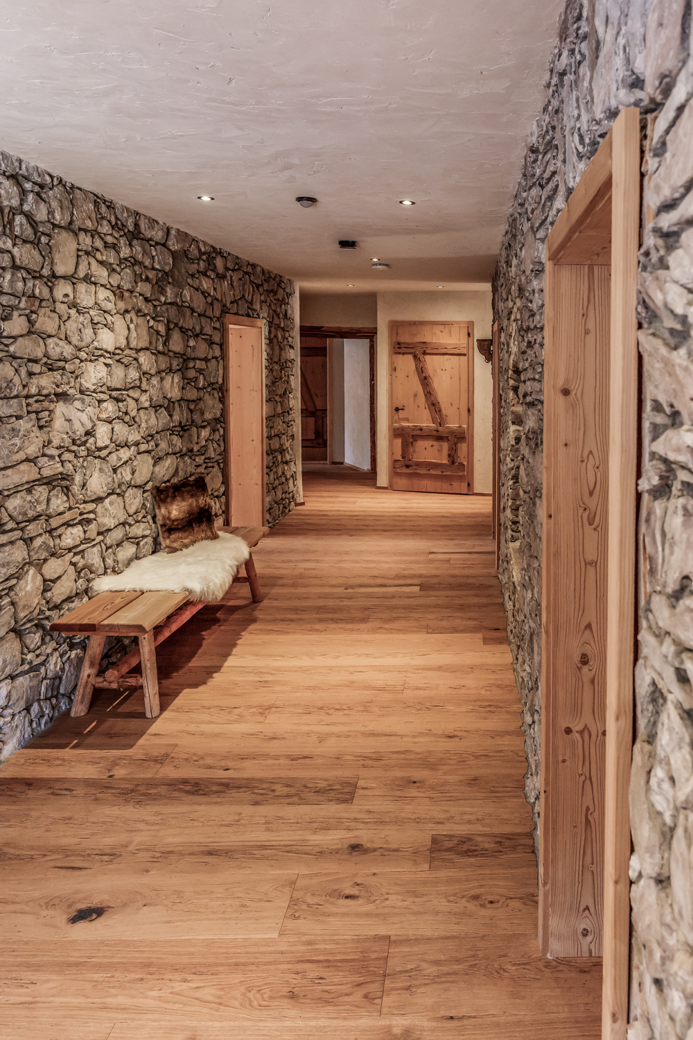 Eingangsbereich der Residence II mit Natursteinwand und Altholztür